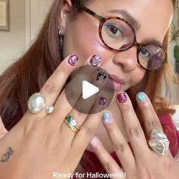 Woman showing finished Coraline-themed Halloween nails (by @nailsby.amy.ito).